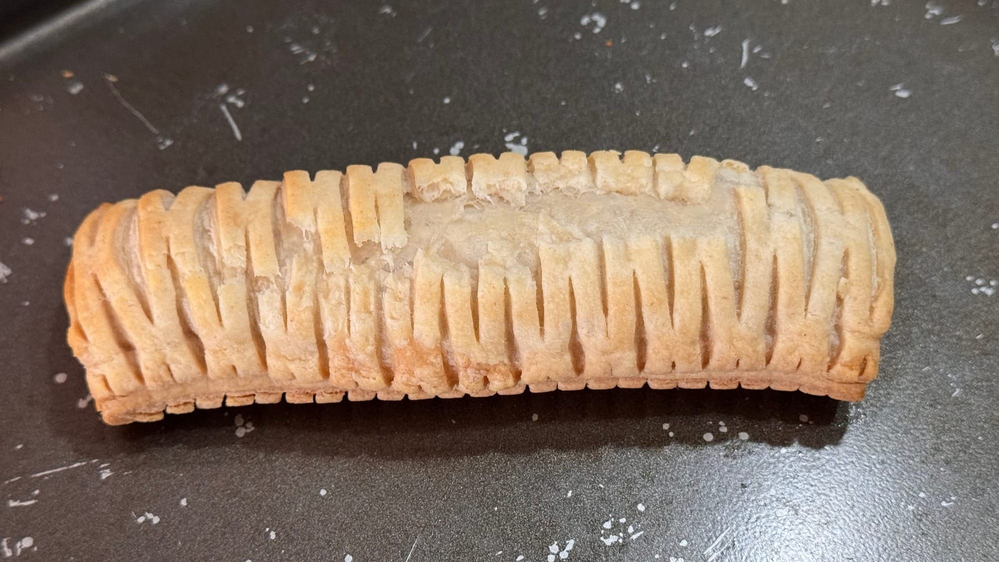 Close-up of a Greggs vegan sausage roll on a baking tray—perhaps a little light on the color, some folks would prefer it stay in the oven in a little longer.